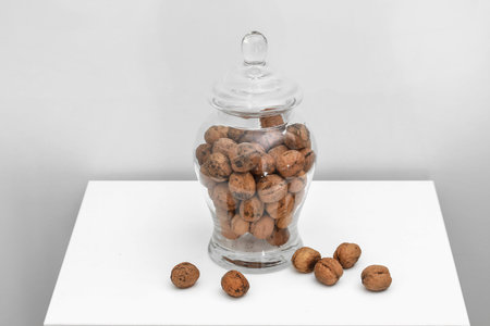 Glass jar with walnuts on table on a white background