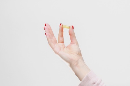 Hand holding capsule of Omega 3 on white background. Close up. High resolution product.の写真素材