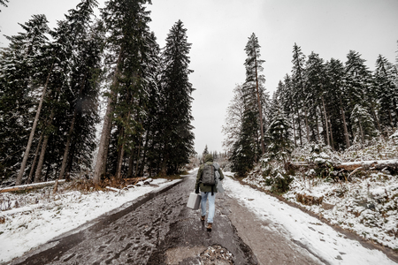 wide angle. tourist man with a backpack going through a snowy forest.の写真素材