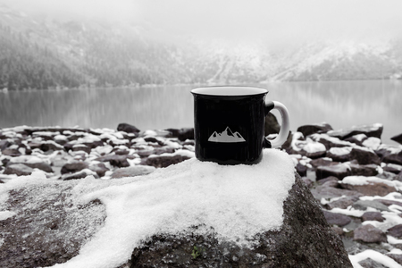 black mug on the background of a mountain lake in winterの写真素材