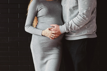 Young couple expecting baby hugging stomachの写真素材