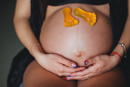 Expectation of the child. A pregnant woman sitting with toy feet.の写真素材