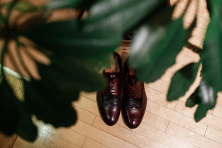 Stylish men's lacquered brown shoes. Wedding accessories groom on rustic wooden background. flat lay.の写真素材