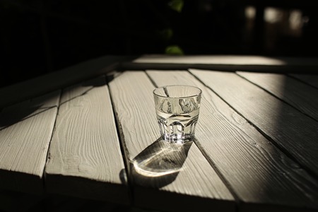 a glass of water on a white table with rays of the sun with nature background.の写真素材