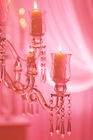 Burning candle in a round glass candlestick with decorative seashells. candles on a glass candlestickの写真素材