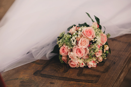 Stylish wedding bouquet bride of pink roses, white carnation and green flowers and greens with ribbons lying. Close up. Side view. Wedding decor. Artwork. beautiful wedding bouquetの写真素材