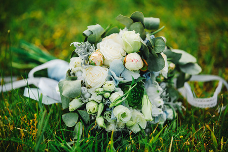 Stylish wedding bouquet bride of pink roses, white carnation and green flowers and greens with ribbons lying. Close up. Side view. Wedding decor. Artwork. beautiful wedding bouquetの写真素材