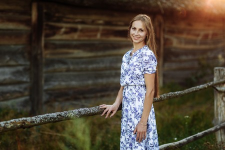 Portrait of a beautiful girl in a blue dress in the field at sunsetの写真素材
