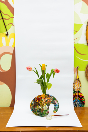 Palette with colorful paints. Colorful oil painting palette with a brush. Paint brushes and paints for drawing. tulips on a white backgroundの写真素材