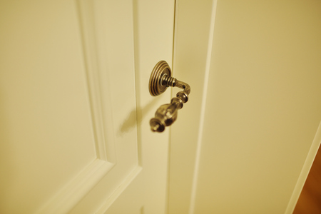 Vintage metal bronze handle in a wooden white door.の写真素材