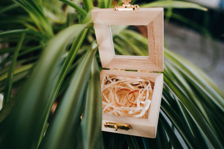 Reflection of the bride and groom in the mirror of wooden box with golden wedding rings which stands...