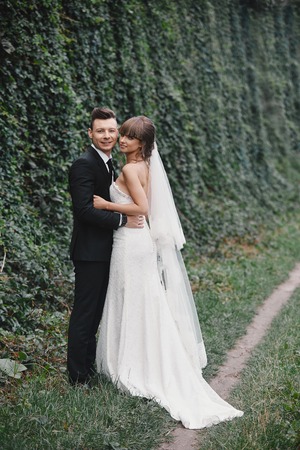 Stylish couple of newlyweds on their wedding day. Happy young bride, elegant groom and wedding bouquet. Portrait of young wedding couple at nature.の写真素材