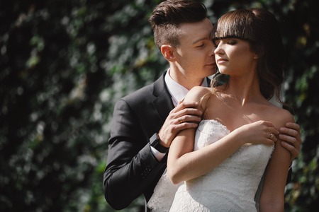 Bride and groom in a park kissing. couple newlyweds bride and groom at a wedding in nature green forest are kissing photo portrait.Wedding Couple. Newlywedsの写真素材