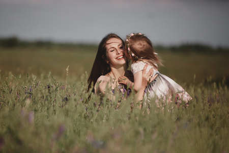 Beautiful Mother And her little daughter outdoors. Nature. Beauty Mum and her Child playing in Park together. Outdoor Portrait of happy family. Happy Mother's Day Joy. Mom and Babyの写真素材