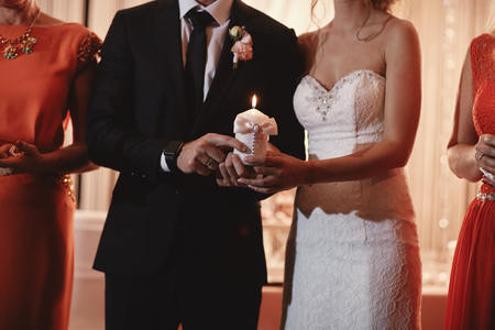Happy bride hold and groom keep a family candle burning on the wedding day after the ceremony. the end of the wedding and the creation of a new family. Traditions and customs.の写真素材