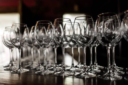 empty wine glasses. Beautiful new glasses for wine from glass stand in even rows on a wooden table in a restaurant. selective focusの写真素材