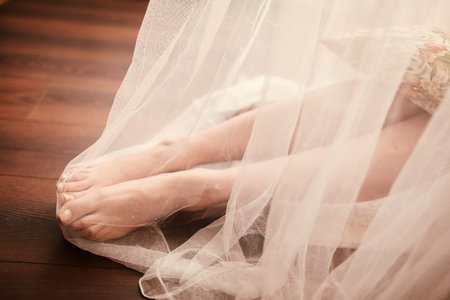 Bride morning preparation. Bride legs in white veil on wooden floor