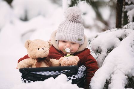 cute little baby boy with teddy bears in winter forest.の写真素材