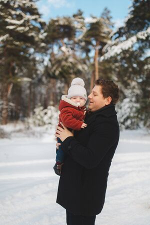 portrait of dad with baby son in winter forest. family has a good time together.の写真素材