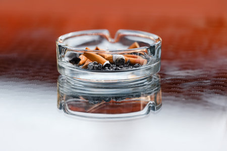 A dirty ashtray with cigarette ash and butts.