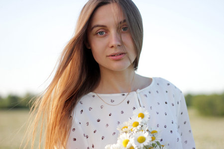 Beautiful young woman enjoying a field of daisies, beautiful girl relaxing outdoors, having fun,...