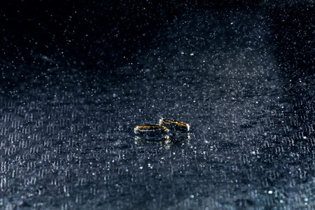 wedding golden rings in water drops on blue background.