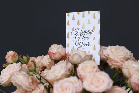 Close up beautiful Fresh pink roses flowers with Happy New Year greeting card on grey background. copy space.の写真素材