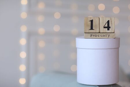Valentine's day concept. Date 14 February on wooden red cube calendar on a white gift box. Bokeh golden and white backgroundの写真素材
