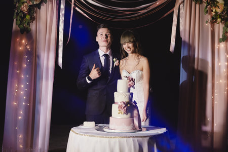 bride and groom stand next to a large wedding cake outside. wedding day.の写真素材