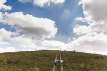 Couple holding hands are walking away. Portrait of a romantic young man and woman in love in nature....