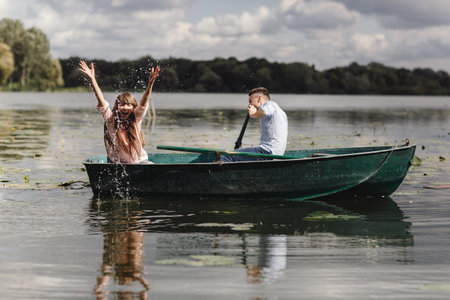Feeling playful. Beautiful young couple enjoying romantic date while rowing a boatの写真素材