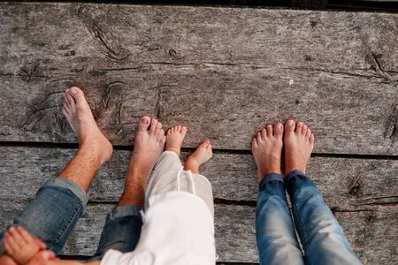 Mom, dad and baby walk bare feet on the wooden bridge. Happy young family spending time together, running outside, go in nature, on vacation, outdoors. The concept of family holiday. copy space.の写真素材