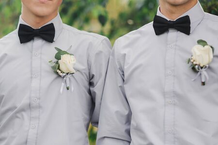 white roses flowers in buttonhole, two grooms friends is dressed in a grey shirt and a bow tie. Wedding day. Outfit of the dayの写真素材