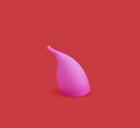 pink reusable silicone menstrual cup isolated on red backgroundの写真素材