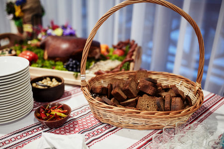 Ukrainian-style table with a basket of bread, peppers and baked pork on a table with Ukrainian...