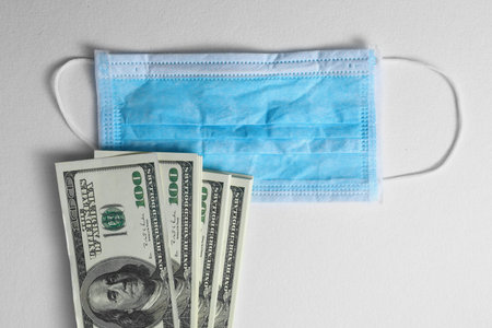 Medical protective masks and and a bundle of dollars, money on white background. Chinese coronavirus...