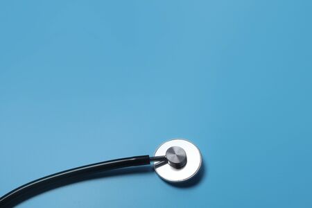 Used stethoscope hanging over blue background ideal for medical and healthcare concept.の写真素材