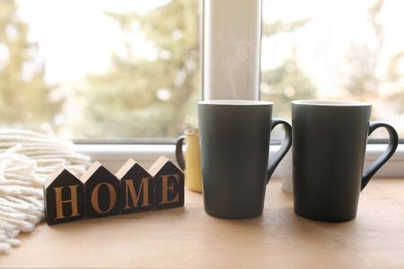 Still life home decor in a cozy house with wooden letters with the inscription home. The concept of decor and comfort. two cups with hot tea. selective focus.の写真素材
