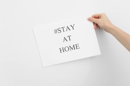 stay at home concept. woman hand holding paper with words stay at home isolated on white background....