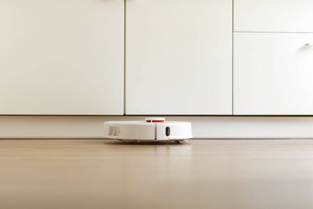 Robot vacuum cleaner performs automatic cleaning of the apartment at a certain time. white robot vacuum cleaner. home cleaning. Smart home. selective focusの写真素材