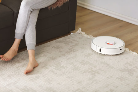 Robotic vacuum cleaner cleaning the room while woman resting on sofa. selective focus on Roboticの写真素材