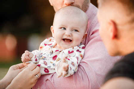 dad is holding little cute smiling daughter in arms. Family spending summer time together, outside,...