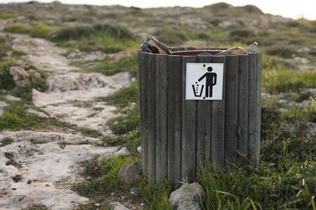 wooden trash or litter bin with for bottle, beer can and organic waste visibile showing pollution in coastal areas near the sea.の写真素材