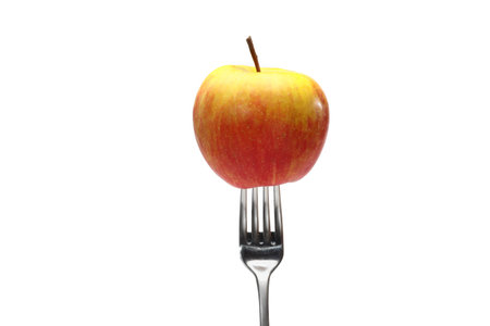 apple on fork on a white background. One ripe organic, juicy, fragrant apple with a metal fork,...