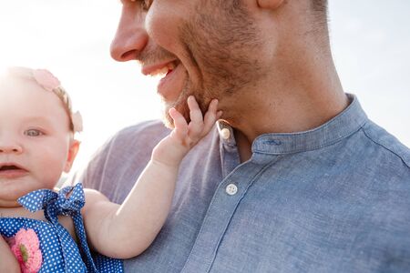 Happy smiling young father and little daughter in his hands having fun outdoors on summer day. family concept. fathers and baby day.の写真素材