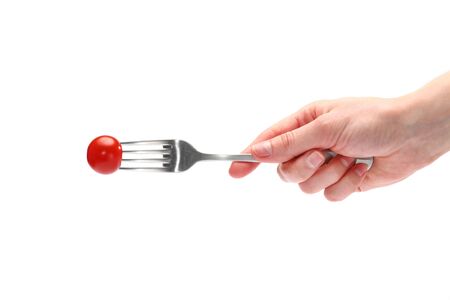female hand holds a dining fork with fresh cherry tomatoes isolated on the white background.の写真素材