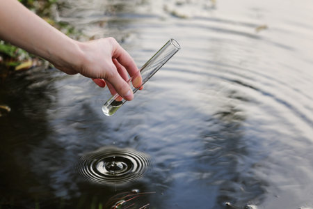 Scientist and biologist hydro-biologist takes water samples for analysis outdoors. Hand is collects...