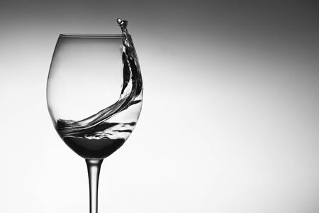 a splash of water in a glass wine glass. water splash in glass on glowing background. transparent liquid splashing in wine glass. Food, objectの写真素材