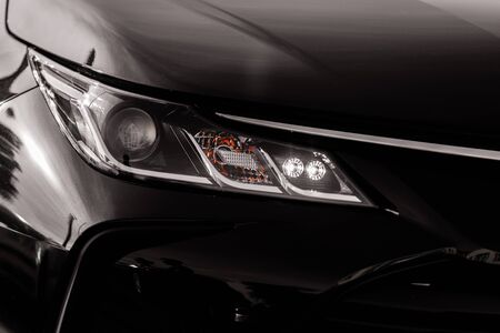 headlight of modern prestigious black car close up. Close up photo of modern car, detail of headlight. Headlight car Projector LED of a modern luxury technology and auto detail.の写真素材