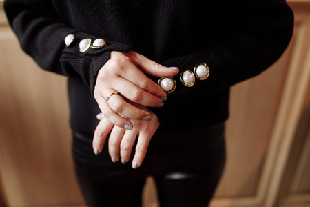 Cropped photo of a stylish woman in black outfit with pearls details. ashion concept.